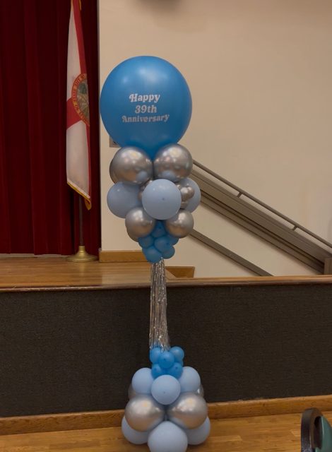 Blue and silver balloon column topped with a personalized anniversary orb