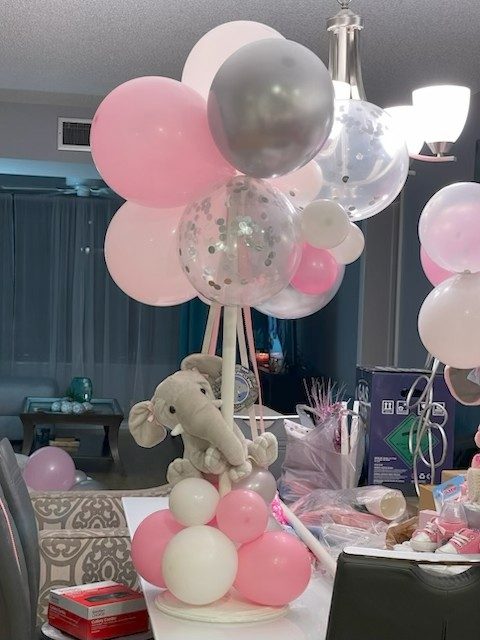Pink and white balloon centerpiece with confetti orbs and a plush elephant