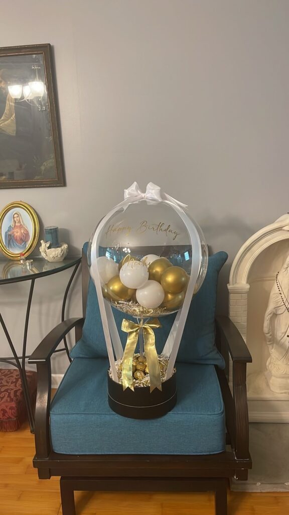 Clear balloon lantern gift filled with white and gold balloons