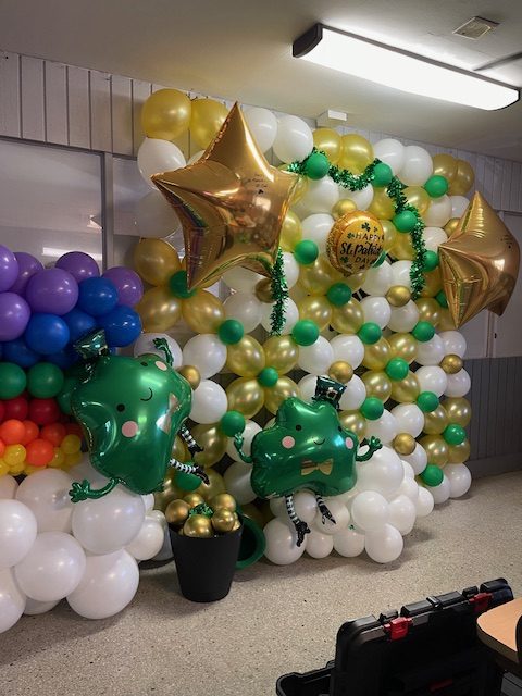 Full balloon wall in green, gold and white with foil stars for a St. Patrick's Day event