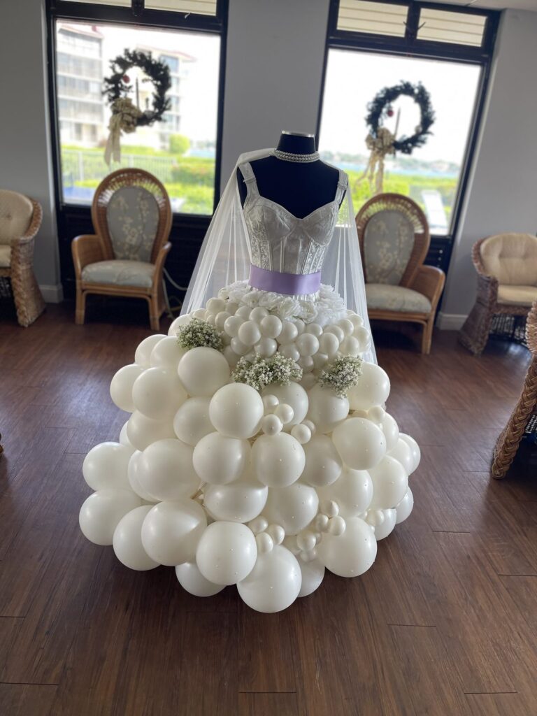 Front view of a white balloon wedding gown sculpture with a lavender sash