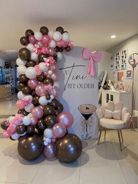 Chocolate brown, blush and rose gold balloon garland beside a martini birthday sign