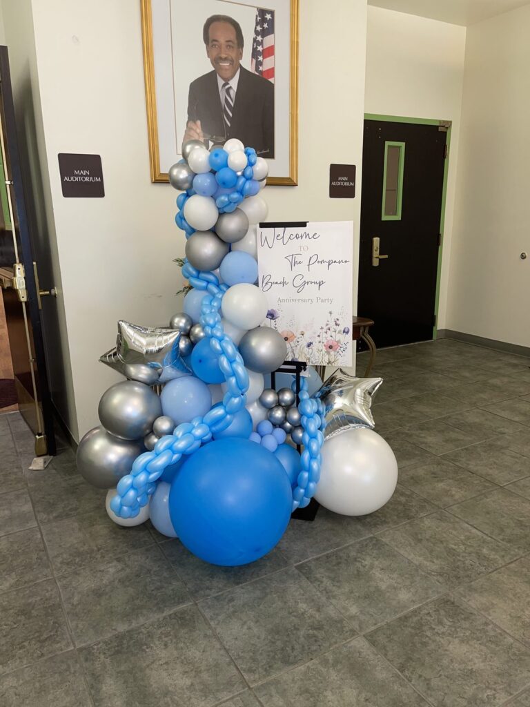 Blue, white and chrome balloon sculpture beside an event welcome sign