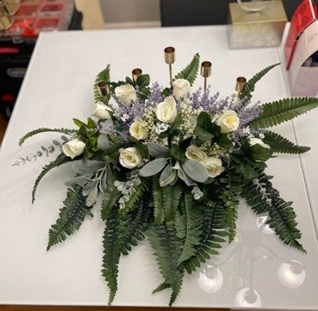 Low floral centerpiece of white roses, lavender and fern with taper candle holders