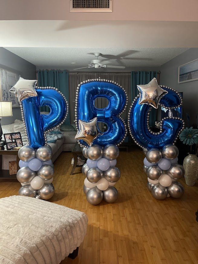 Royal blue foil letter balloons on silver and chrome columns spelling a monogram