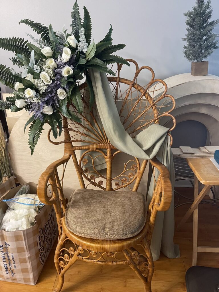 White blooms and greenery styled on a rattan peacock chair