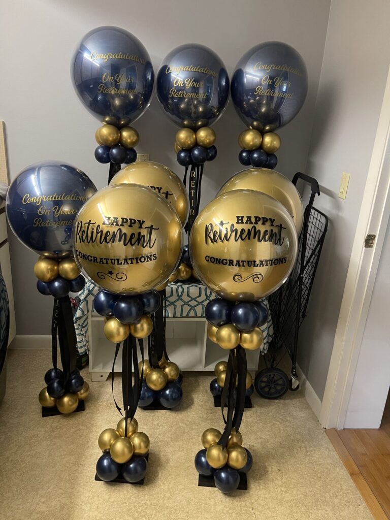 Navy and gold balloon columns topped with happy retirement orbs