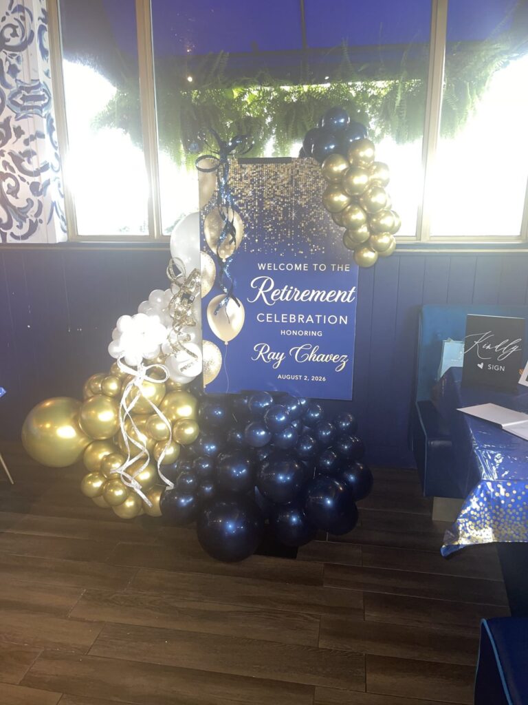 Gold and navy balloon garland wrapping a retirement welcome sign