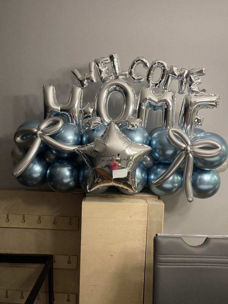 Silver WELCOME HOME foil letters over a blue and chrome balloon base